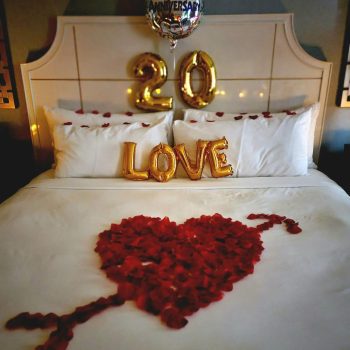A bed with roses and balloons on it