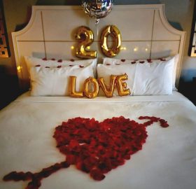 A bed with roses and balloons on it