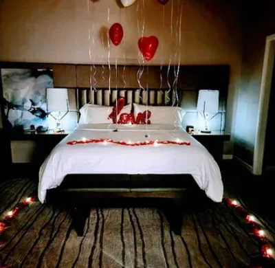 A bed with balloons and candles on the floor.