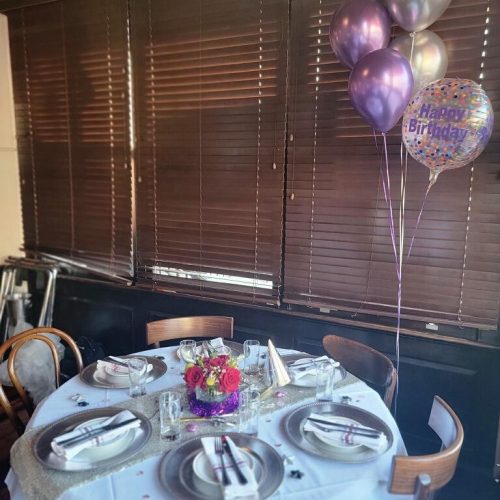 A table set with plates and silverware, and balloons.