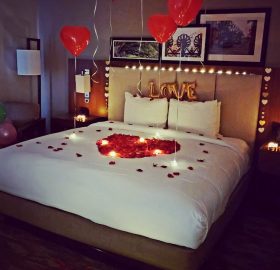 A bed with balloons and candles on the floor