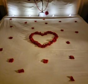 A bed with roses on it and a heart shaped pillow.