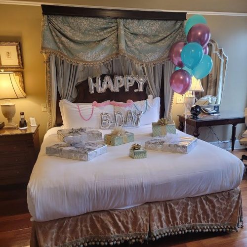 A bed with balloons and presents on it