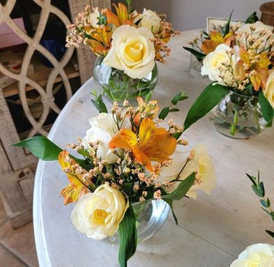 A table with four vases of flowers on it.